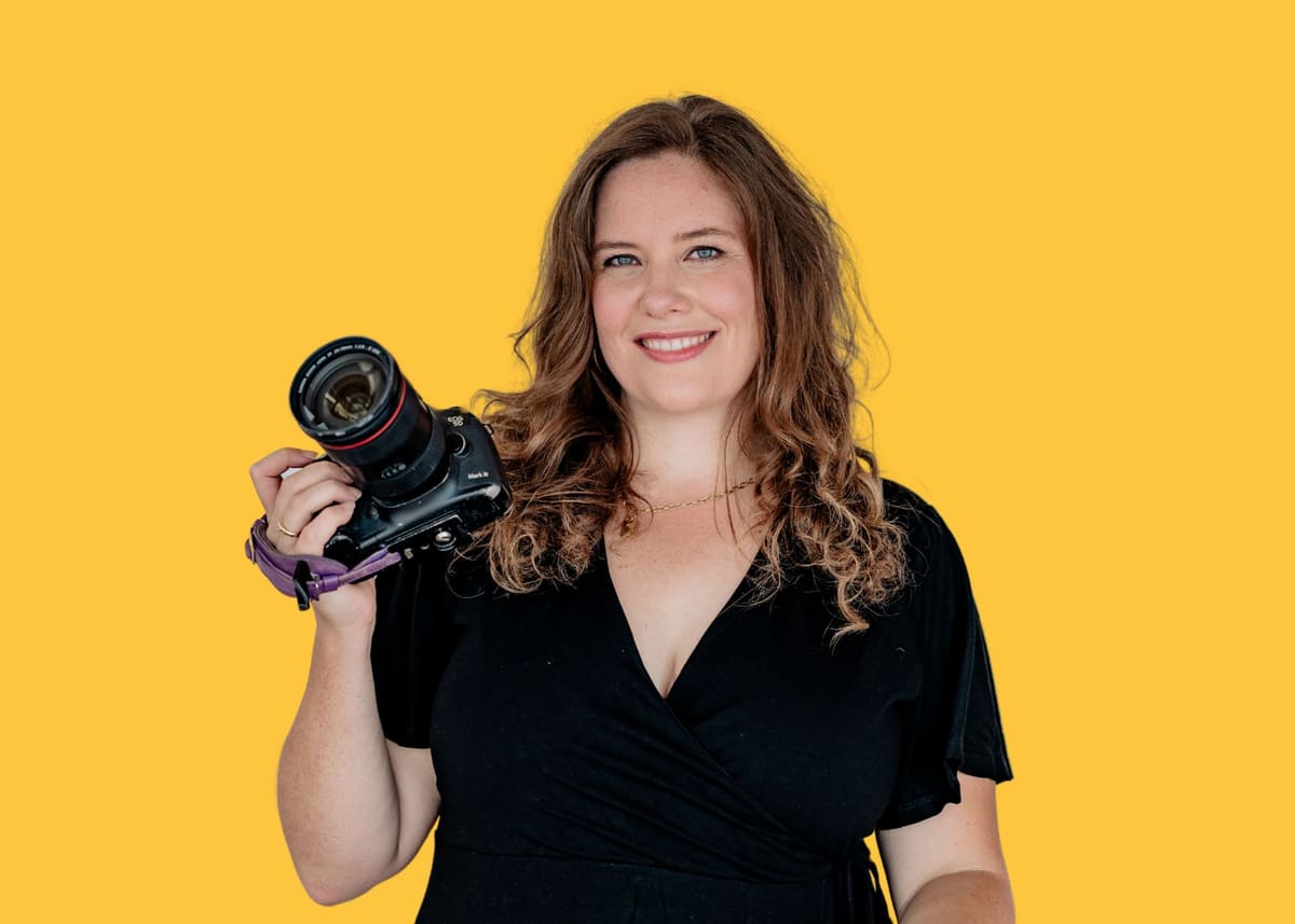 Fotografin Bianca Kübler mit Kamera vor gelbem Hintergrund