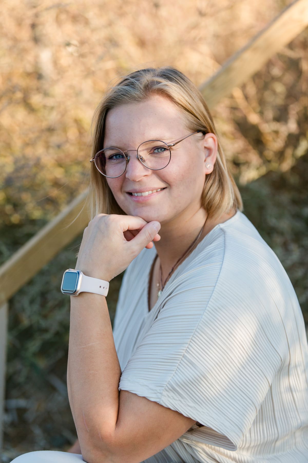 Frau mit Brille stützt das Kinn in die Hand, warmes Abendlicht