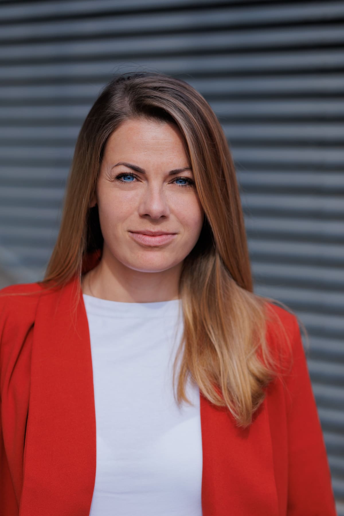 Frau im roten Blazer vor einem grauen Rolltor