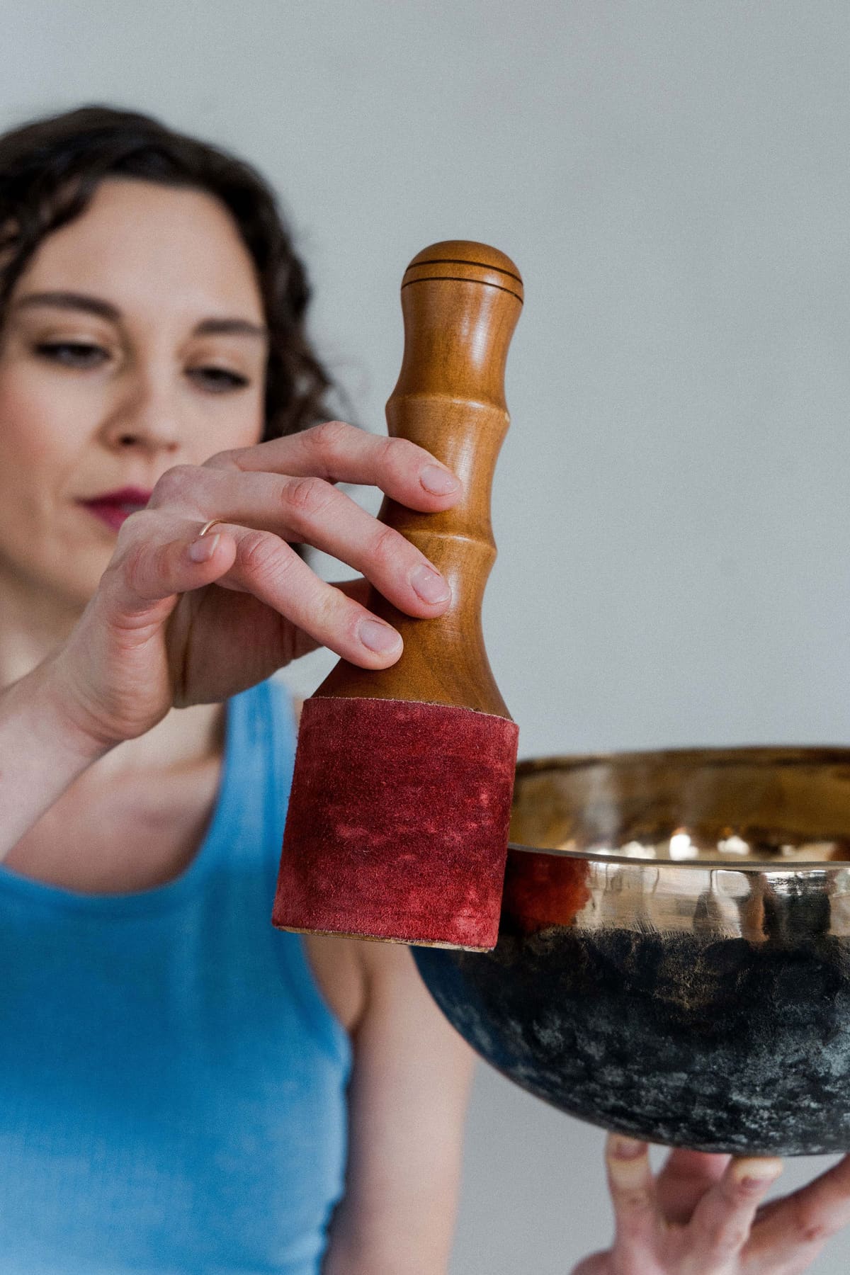 Frau schlägt eine Klangschale mit einem Holzschlegel an, Nahaufnahme