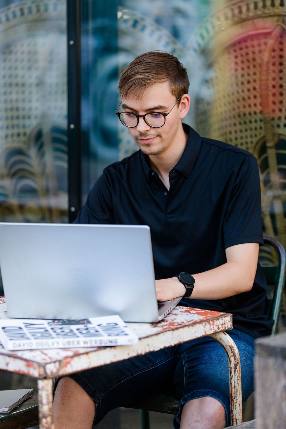 Arbeitssituation im Café Junger Mann mit Brille arbeitet am Laptop in einem Café